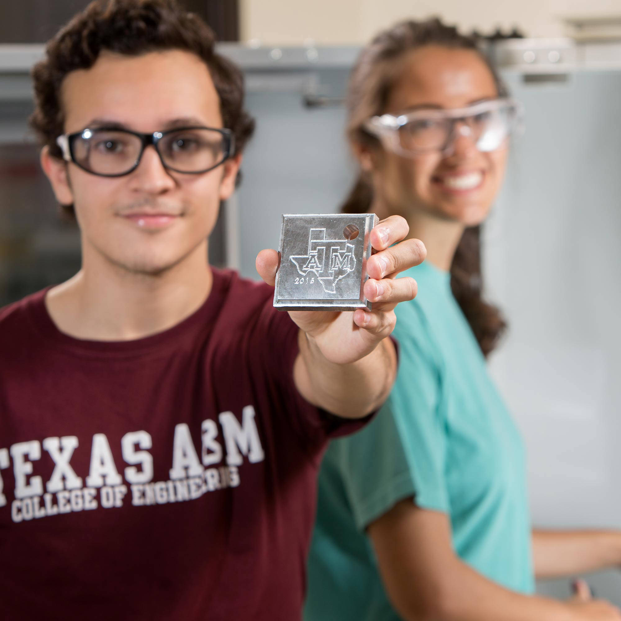 college of engineering student showing 3D printed A&M logo