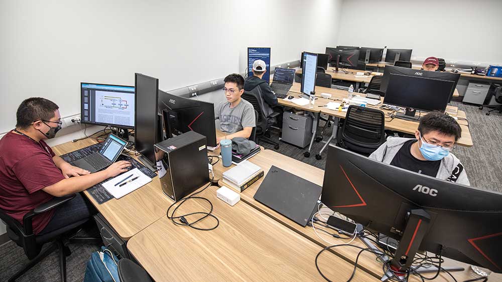 五个男生在一个大的计算机实验室里使用各自的工作站。
