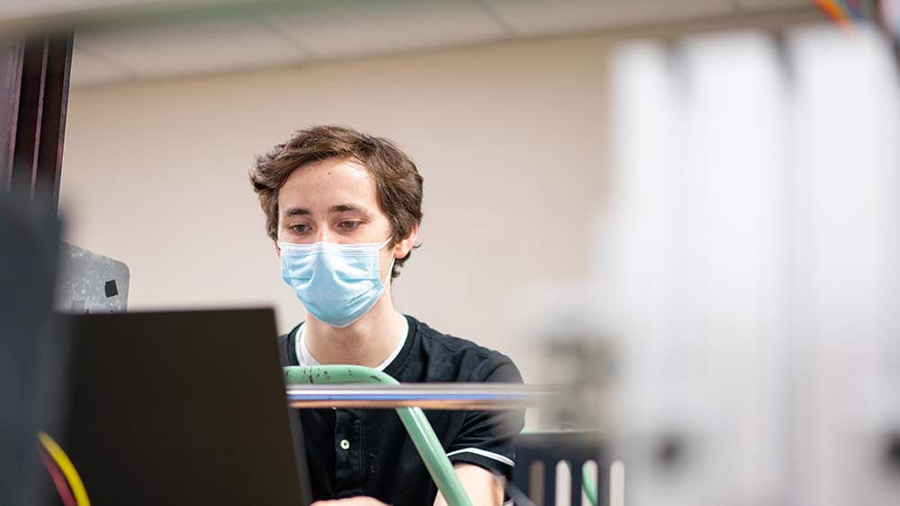 一个男人坐在实验室里，脸上戴着一个蓝色的面具。