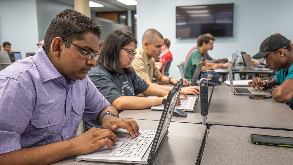 Several male and female Texas A&M at Galveston students working on laptops in classroom.