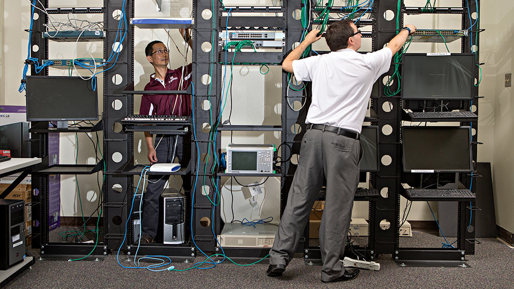 两个男人在技术设备架上工作的广角镜头。