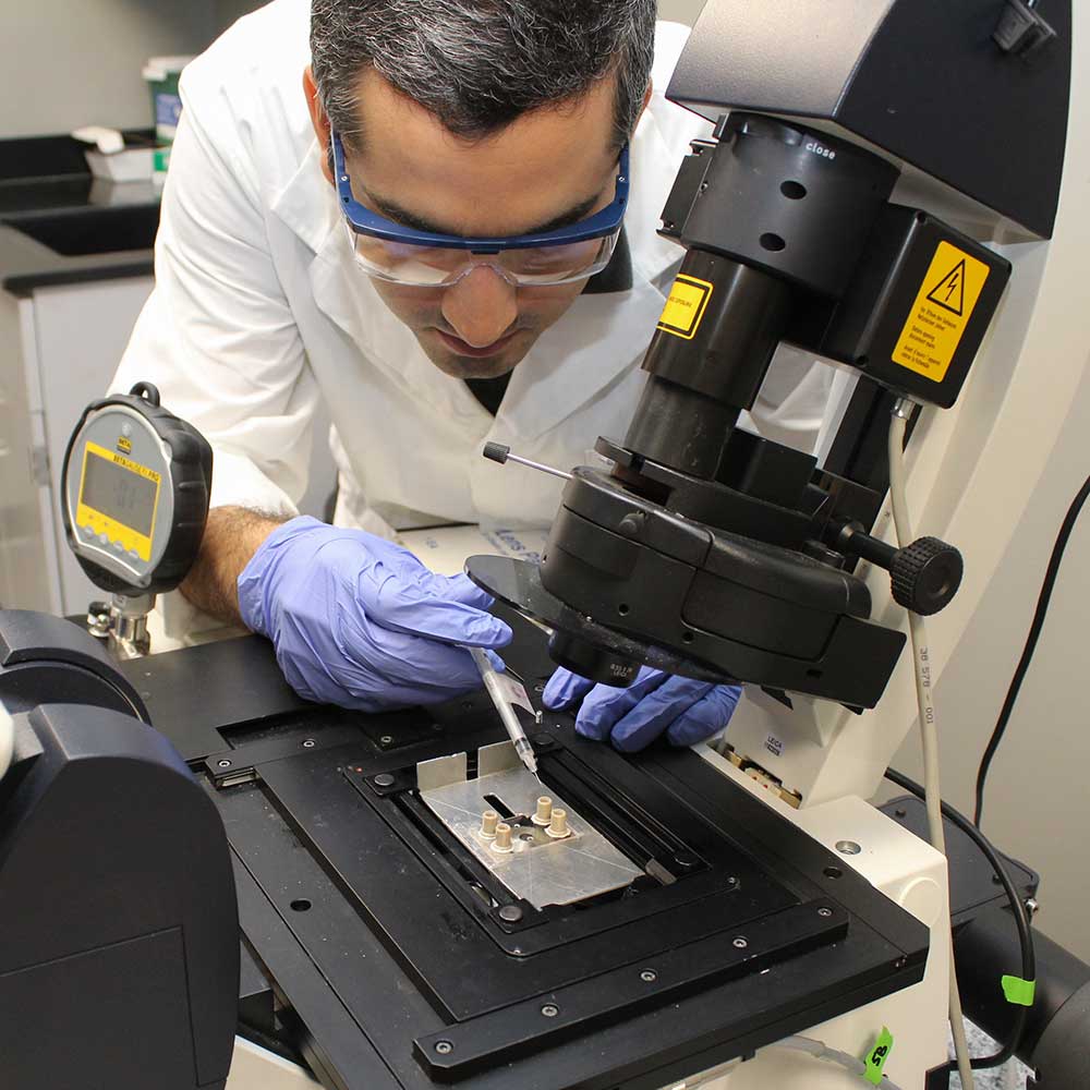 科学家在倒置显微镜上向微流体实验中注入溶液。