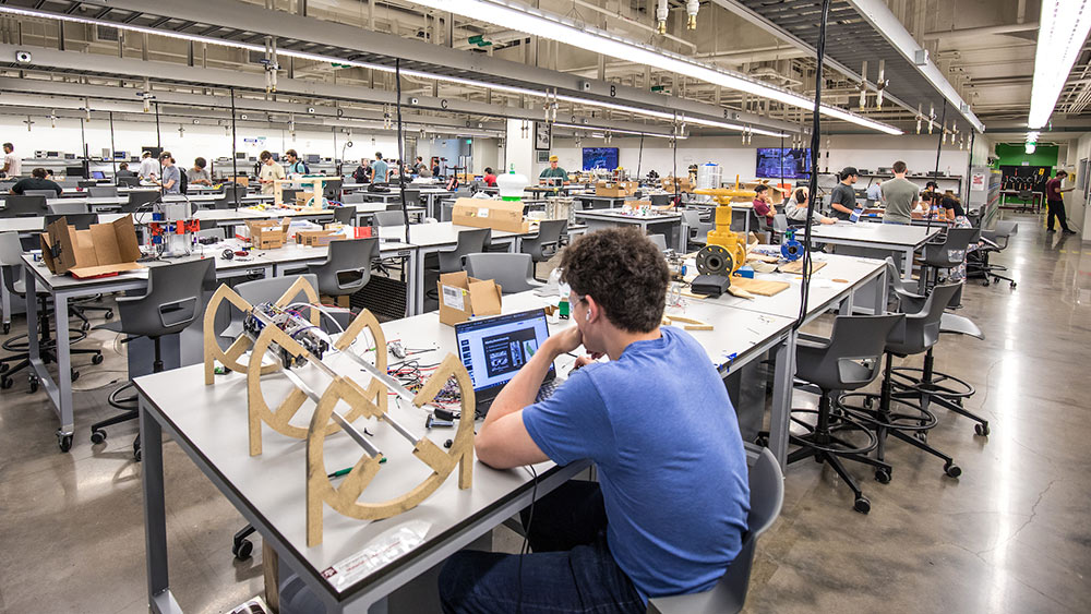 interior shot of design center workspace with lines of tables and students working.