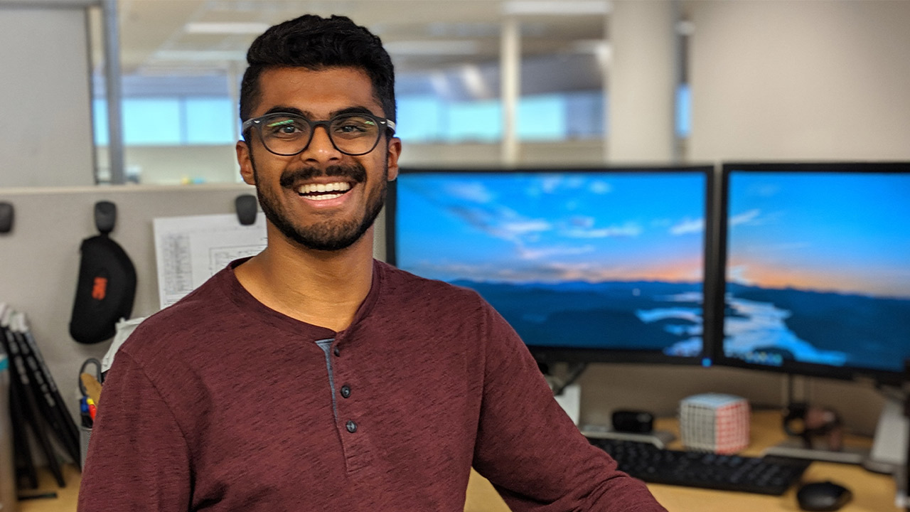 An engineering student smiles, wearing a maroon shirt