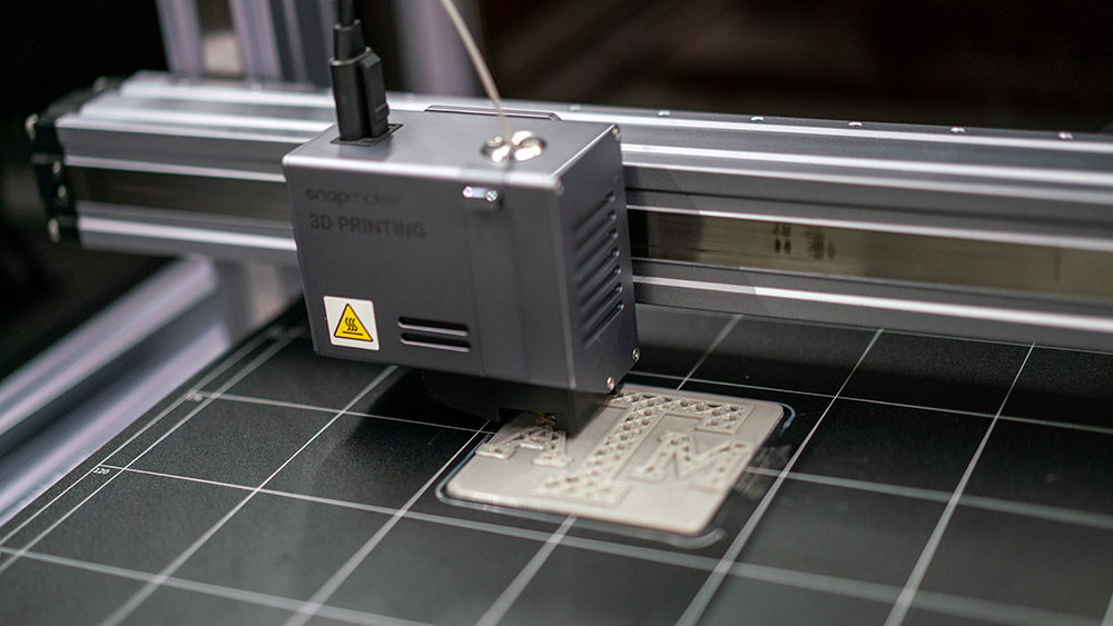 A 3D printer printing the block Texas A&M logo.