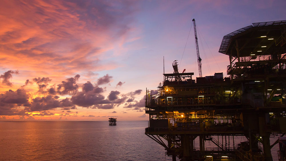 Oil platform over the water with the sunset in the background.