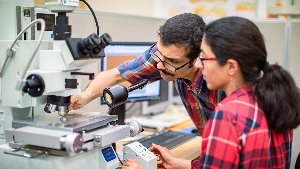 Two students, male and female, working with some technical equipment in the metrology lab.